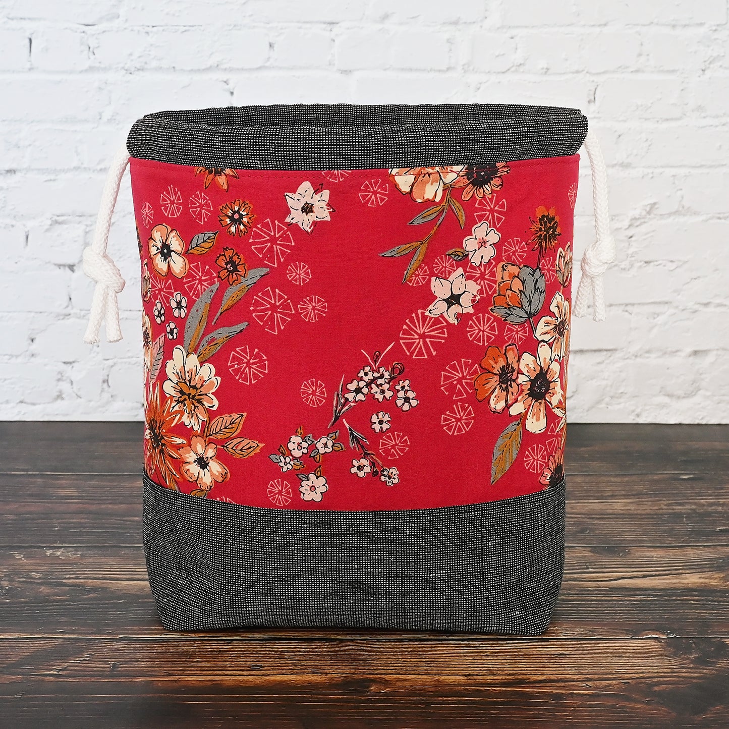 Striking red and charcoal grey project bag with pockets. Made from a beatuiful red floral from Art Gallery Fabrics and paired with a charcoal grey homespun linen from Robert Kaufman. This bag has a secure double drawstring and pockets and it is lightly structured to stand alone.