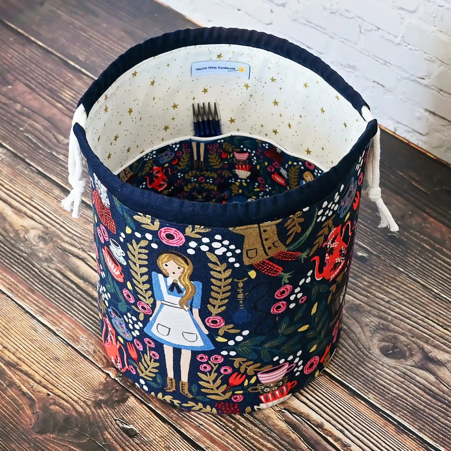 Gorgeous navy bucket bag made from canvas with a beautiful Alice in Wonderland pattern. It has lots of pockets and is structured to stand alone. Made in Canada by Yellow Petal Handmade.