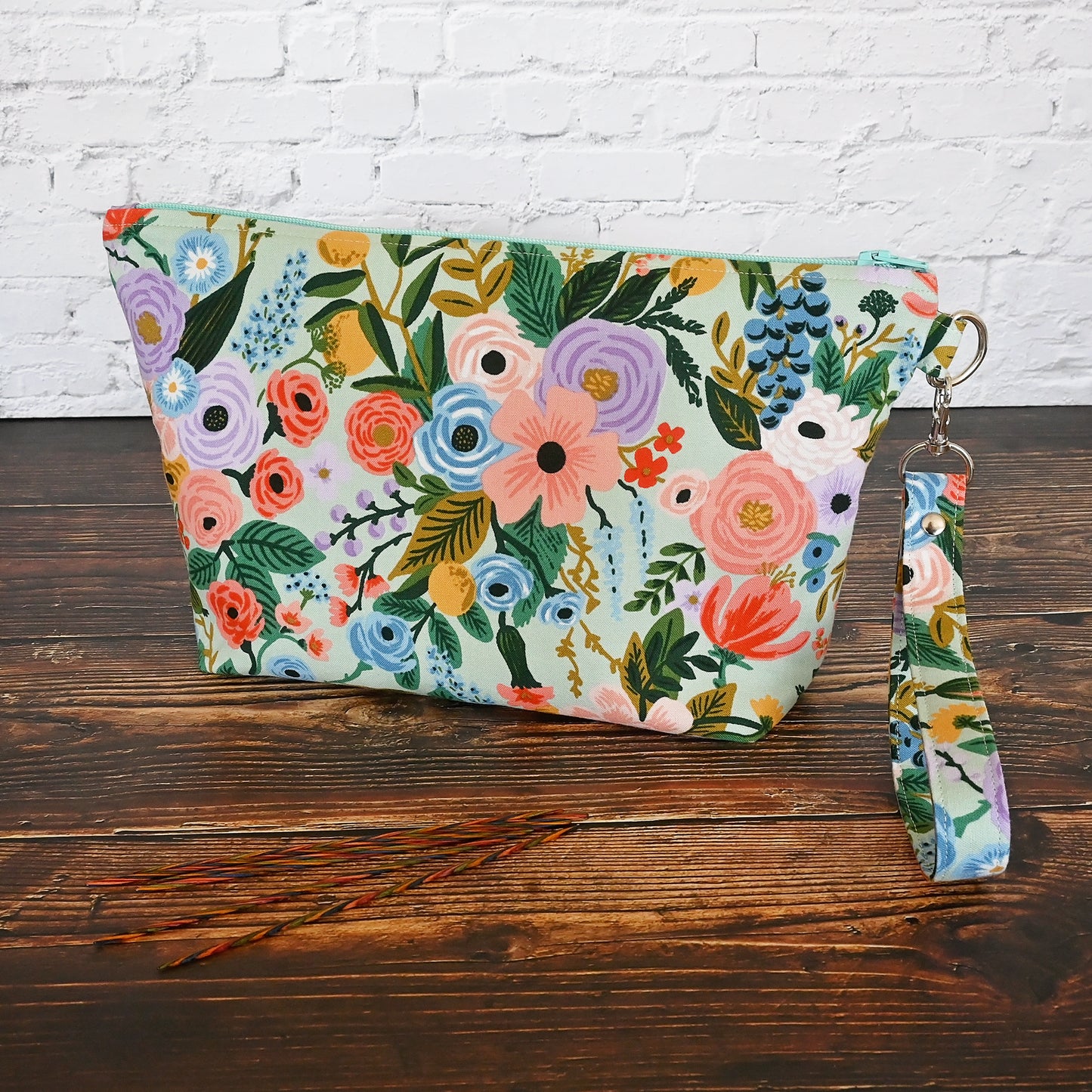 Aqua floral pouch with zipper closure and a removable wrist strap. Made from Rifle Paper Co's newest garden party collection and lined in a pale pink spotty fabric. Made in Canada by Yellow Petal Handmade.