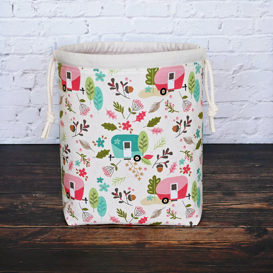 Fun camping themed project bag with pockets and a drawstring closure.  Made from the Glamp Camp collection by Riley Blake, the exterior features vintage campers along with some trees and foliage.  The interior is lined with a pretty pink and white spotty fabric from Dear Stella.  Made in Nova Scotia, Canada by Yellow Petal Handmade.