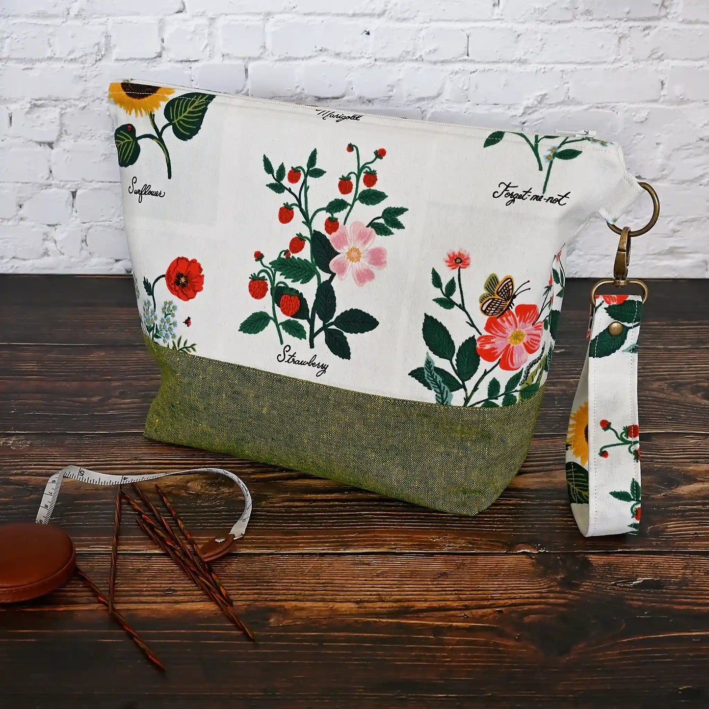 Stunning white canvas floral project bag, paired with a lovely green linen. This bag has pockets, closes with a zipper and has a lovely removable wrist strap. Made in Canada by Yellow Petal Handmade.