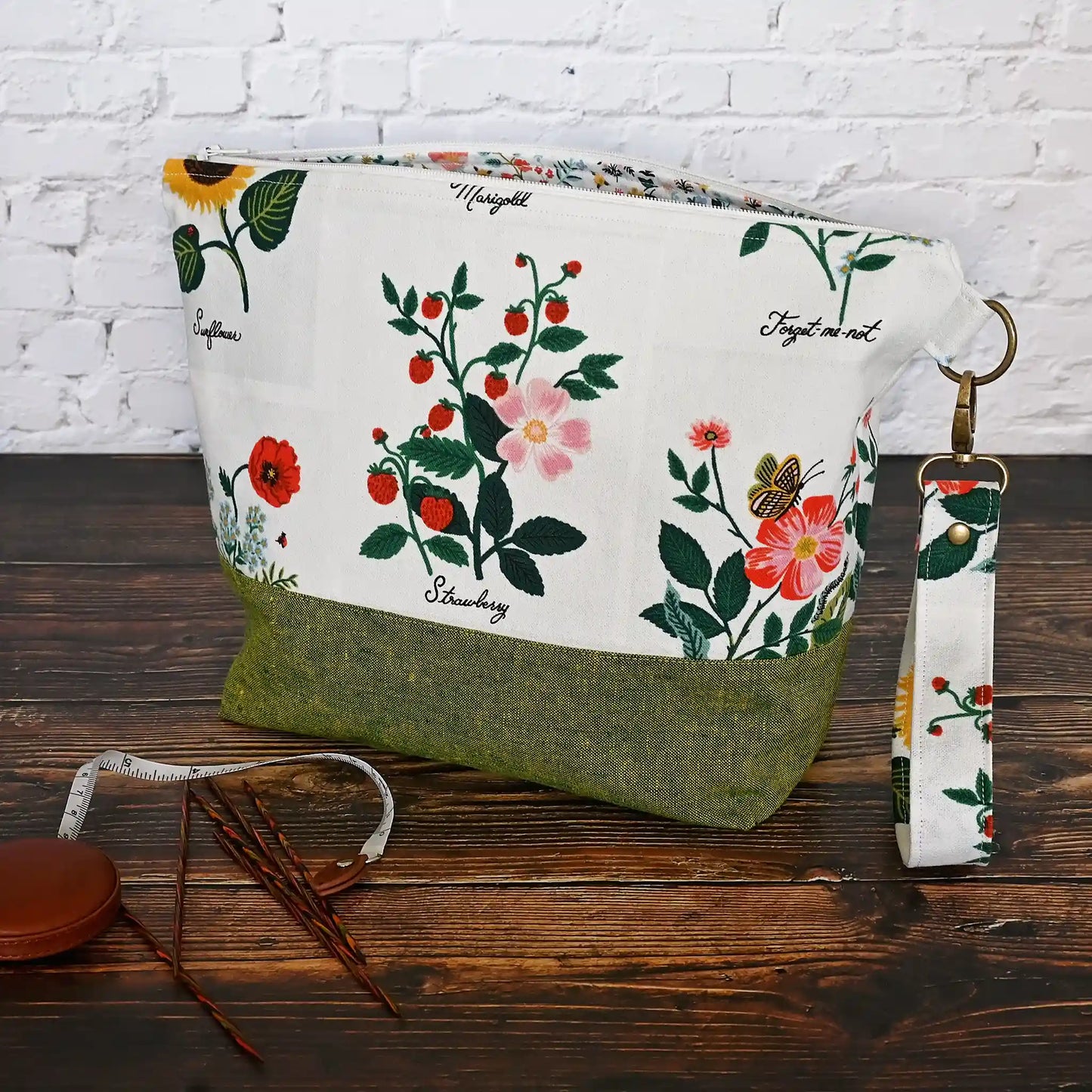 Stunning white canvas floral project bag, paired with a lovely green linen. This bag has pockets, closes with a zipper and has a lovely removable wrist strap. Made in Canada by Yellow Petal Handmade.