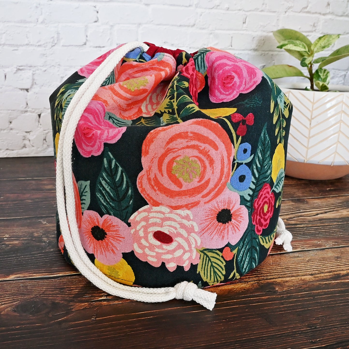 Beautiful canvas bucket bag for knitting or crochet projects.  Made from Rifle Paper Co's English Garden collection, this bag features a dark background with brightly colour flowers on the exterior.  The drawstring casing is made from a pretty burgundy linen and the bag is lined in a lovely dove coloured cotton with gold accents.  This bag features many interior pockets and folds down nicely while using for eacy access.