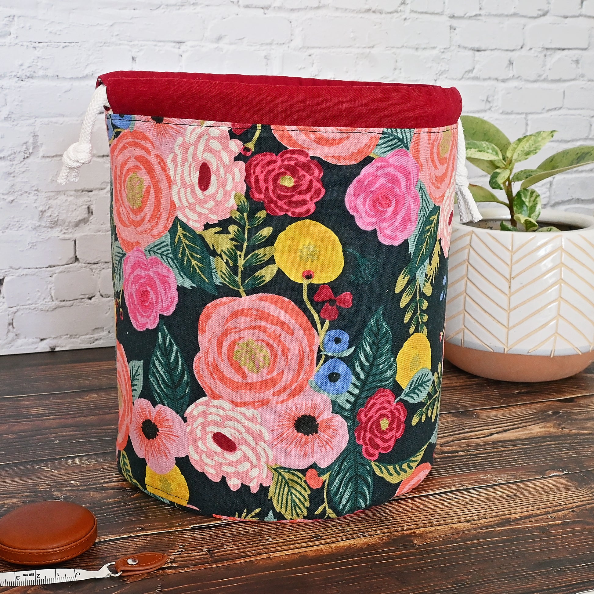 Beautiful canvas bucket bag for knitting or crochet projects.  Made from Rifle Paper Co's English Garden collection, this bag features a dark background with brightly colour flowers on the exterior.  The drawstring casing is made from a pretty burgundy linen and the bag is lined in a lovely dove coloured cotton with gold accents.  This bag features many interior pockets and folds down nicely while using for eacy access.