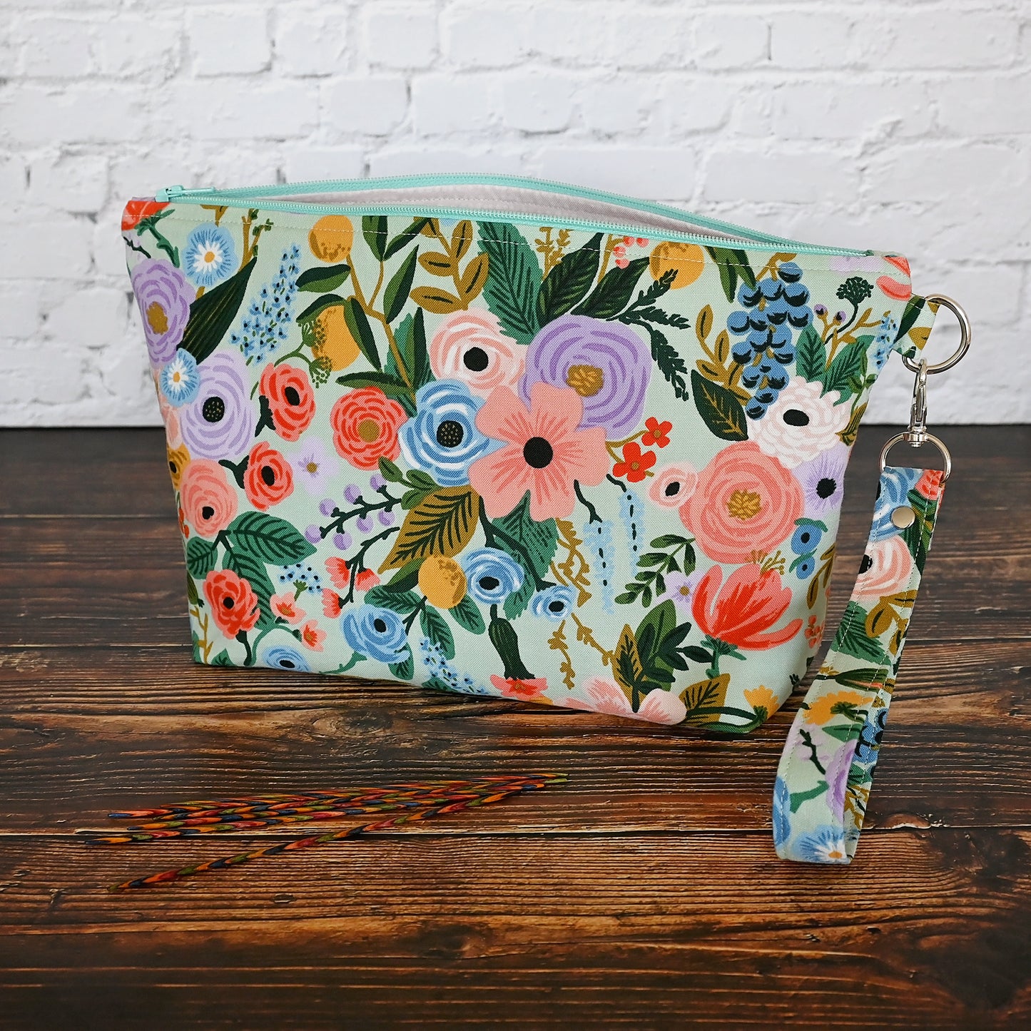 Aqua floral pouch with zipper closure and a removable wrist strap. Made from Rifle Paper Co's newest garden party collection and lined in a pale pink spotty fabric. Made in Canada by Yellow Petal Handmade.