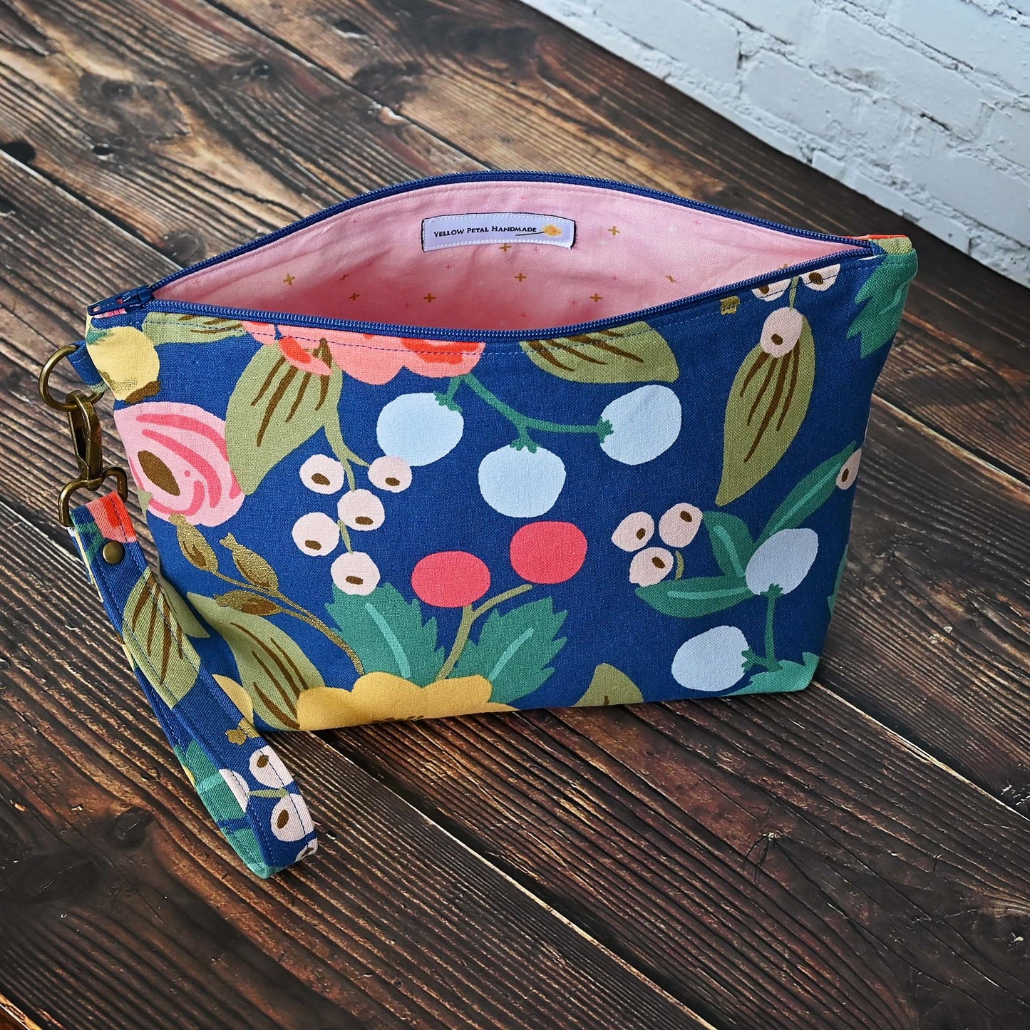 Blue floral canvas zippered pouch with removable wrist strap, lined in a pretty pink cotton. Made with fabric from Rifle Paper Co and Riley Blake. Handmade in Canada by Yellow Petal Handmade.
