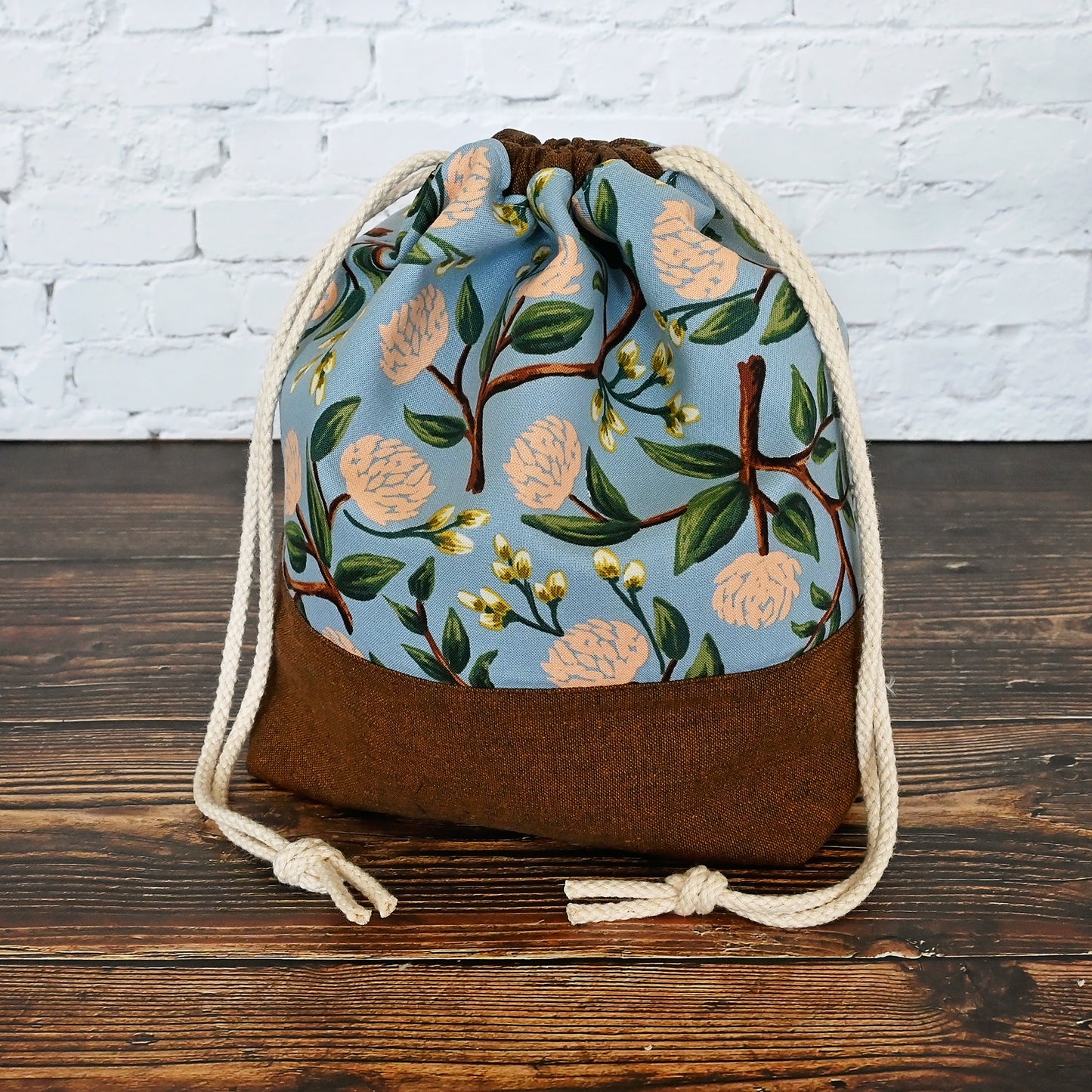 Pretty floral project bag in peonies fabric by Rifle Paper Co, paired with a lovely brown linen from Robert Kaufman. This bag is lined with a pale peach fabric and closes securely with a double drawstring. Made in Canada by Yellow Petal Handmade.