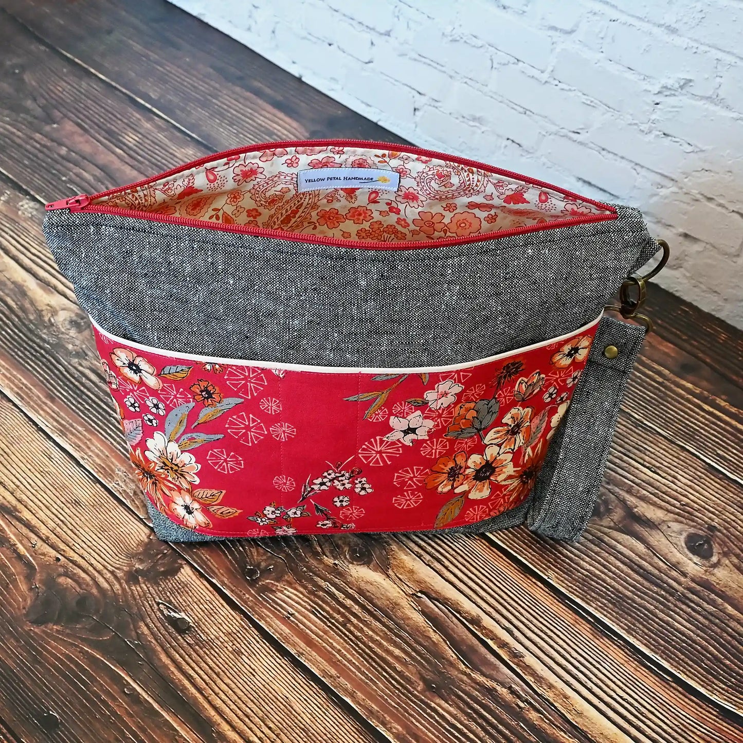 Beautiful grey linen project bag with red floral exterior pockets in  premium Art Gallery cotton.  Comes with a removal wrist strap.  Lined in a fun floral and paisley print.  Made in Nova Scotia Canada by Yellow Petal Handmade.