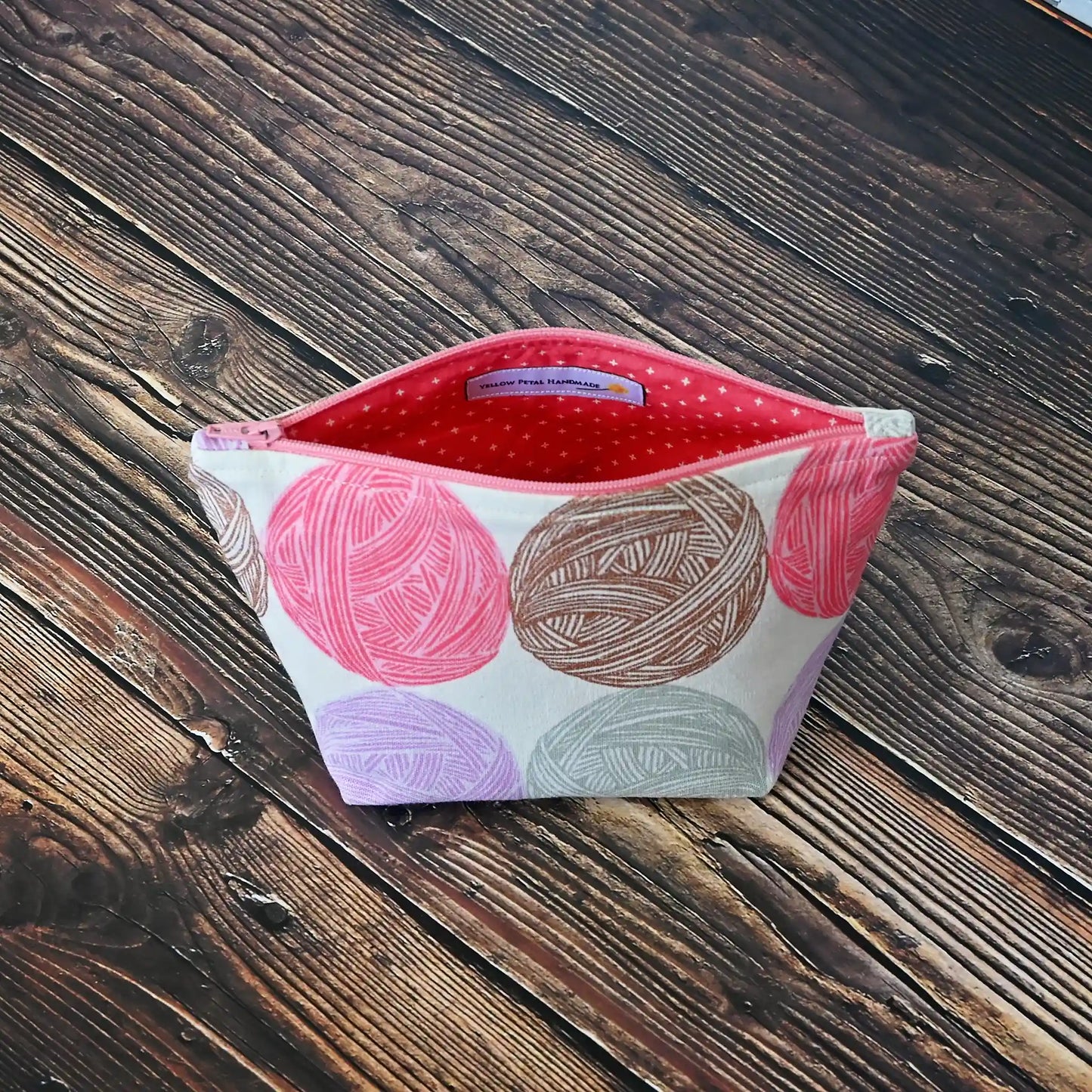 Cute Yarn Balls canvas pouch measuring 8" wide by 5" tall and with a 3.5" boxed bottom. Fabric has cute yarn balls with metallic copper detailing. Made in Canada by Yellow Petal Handmade.