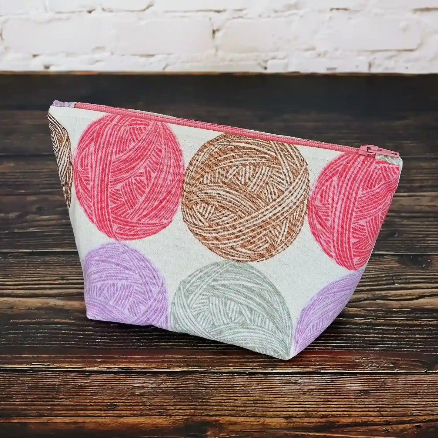 Cute Yarn Balls canvas pouch measuring 8" wide by 5" tall and with a 3.5" boxed bottom. Fabric has cute yarn balls with metallic copper detailing. Made in Canada by Yellow Petal Handmade.