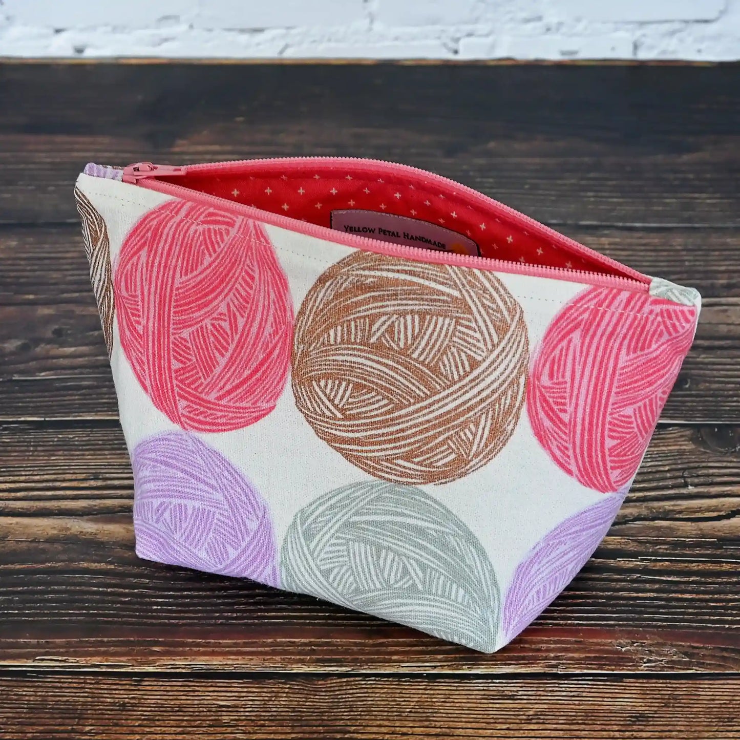 Cute Yarn Balls canvas pouch measuring 8" wide by 5" tall and with a 3.5" boxed bottom. Fabric has cute yarn balls with metallic copper detailing. Made in Canada by Yellow Petal Handmade.