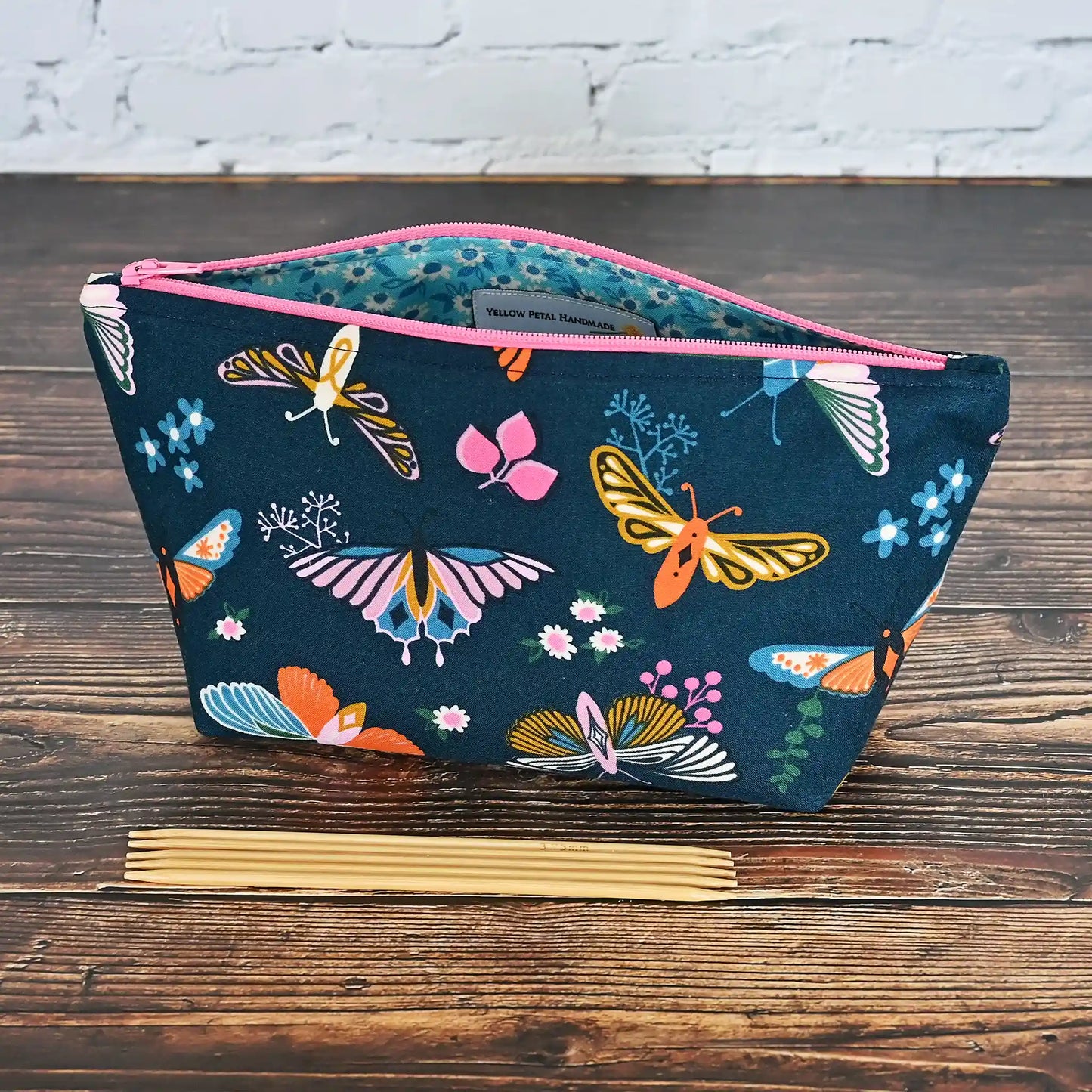 Beautiful navy accessory pouch with butterflies. Lined in a pretty aqua floral and adorned with a pink zipper. Made in fabrics by the Ruby Star Society. Handmade in Canada by Yellow Petal Handmade.