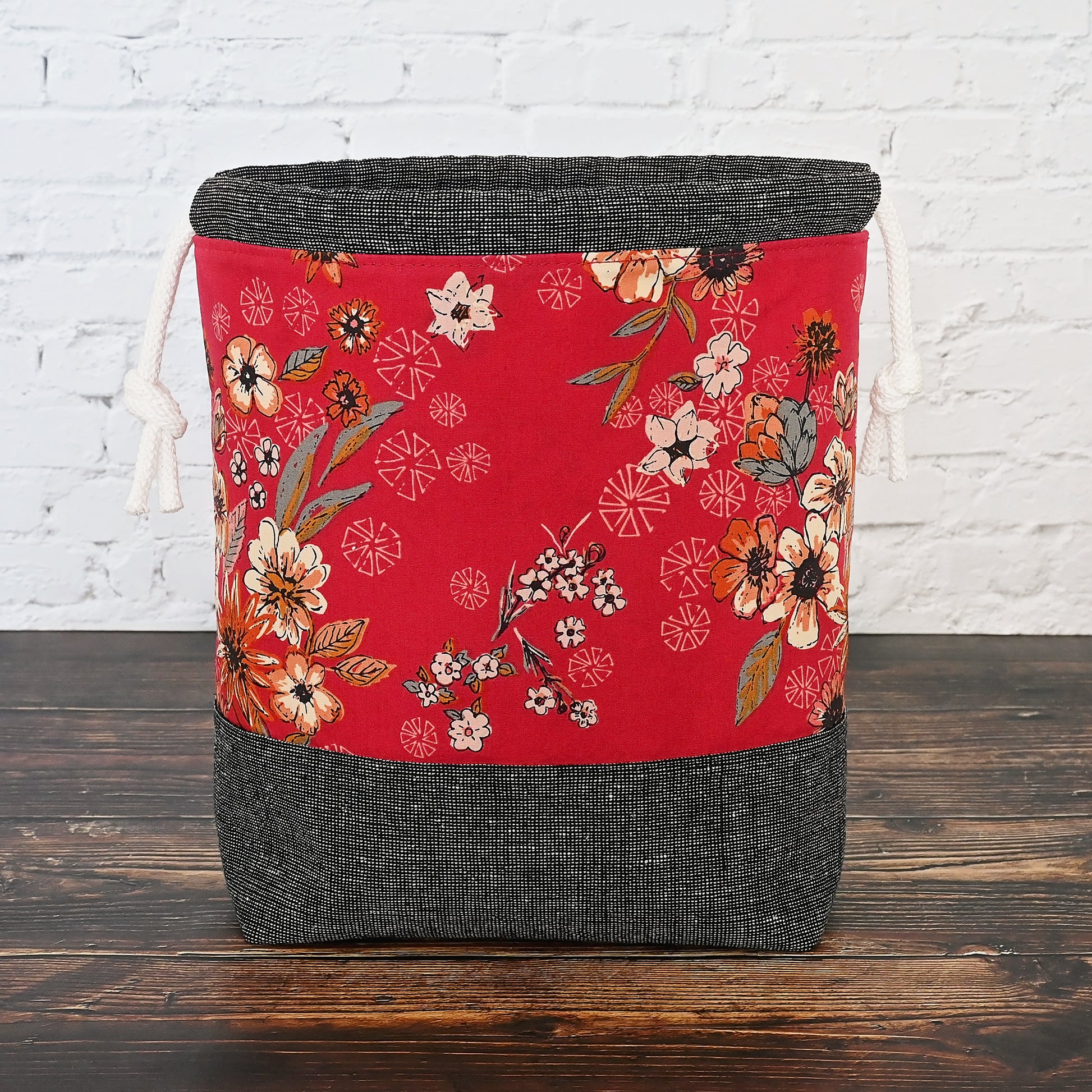 Striking red and charcoal grey project bag with pockets.  Made from a beatuiful red floral from Art Gallery Fabrics and paired with a charcoal grey homespun linen from Robert Kaufman.  This bag has a secure double drawstring and pockets and it is lightly structured to stand alone.