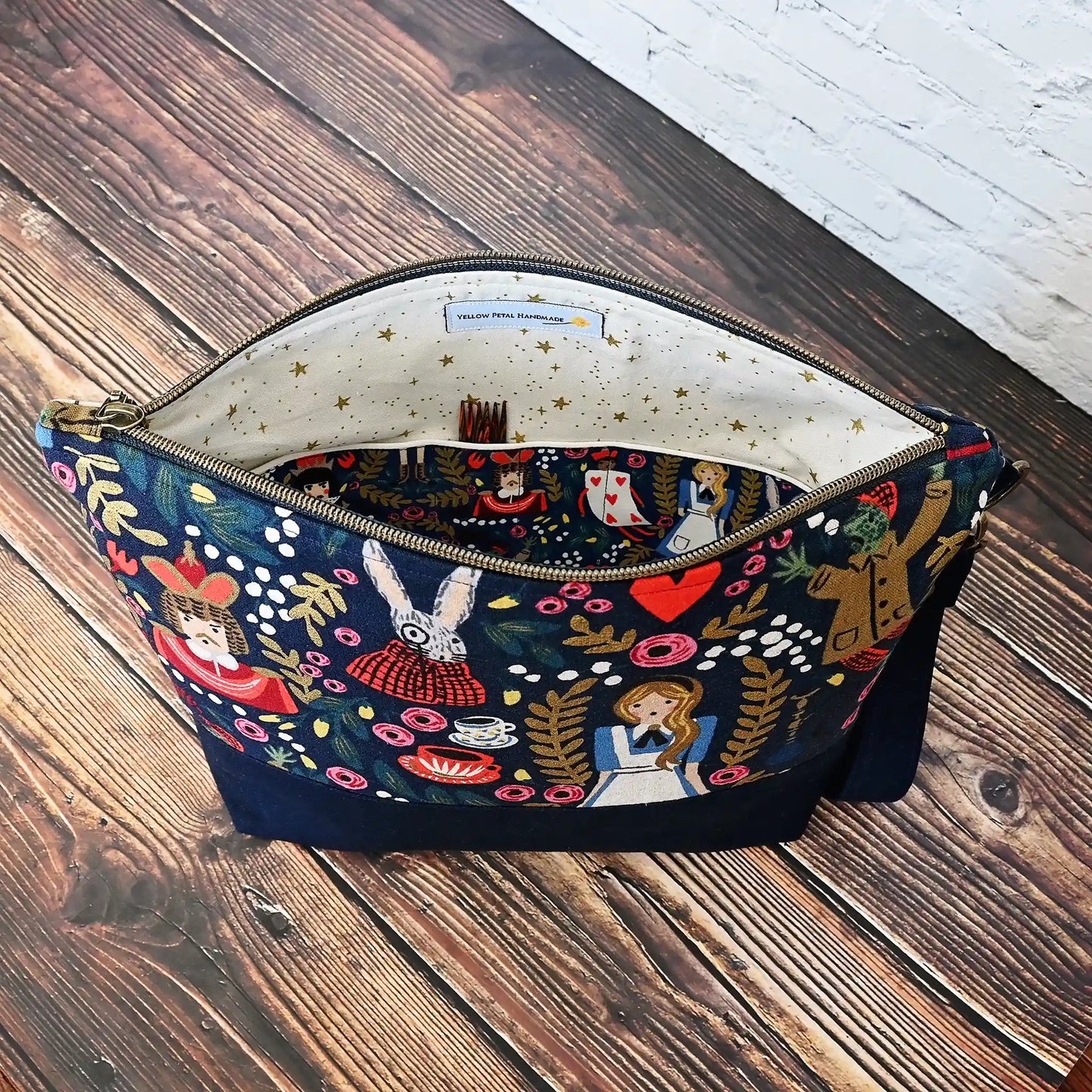 Whimsical navy project bag in Alice in Wonderland Canvas by Rifle Paper Co.  Features a cream  interior with pockets, a zipper closure and a removable wrist strap.  Made in Canada by Yellow Petal Handmade. 
