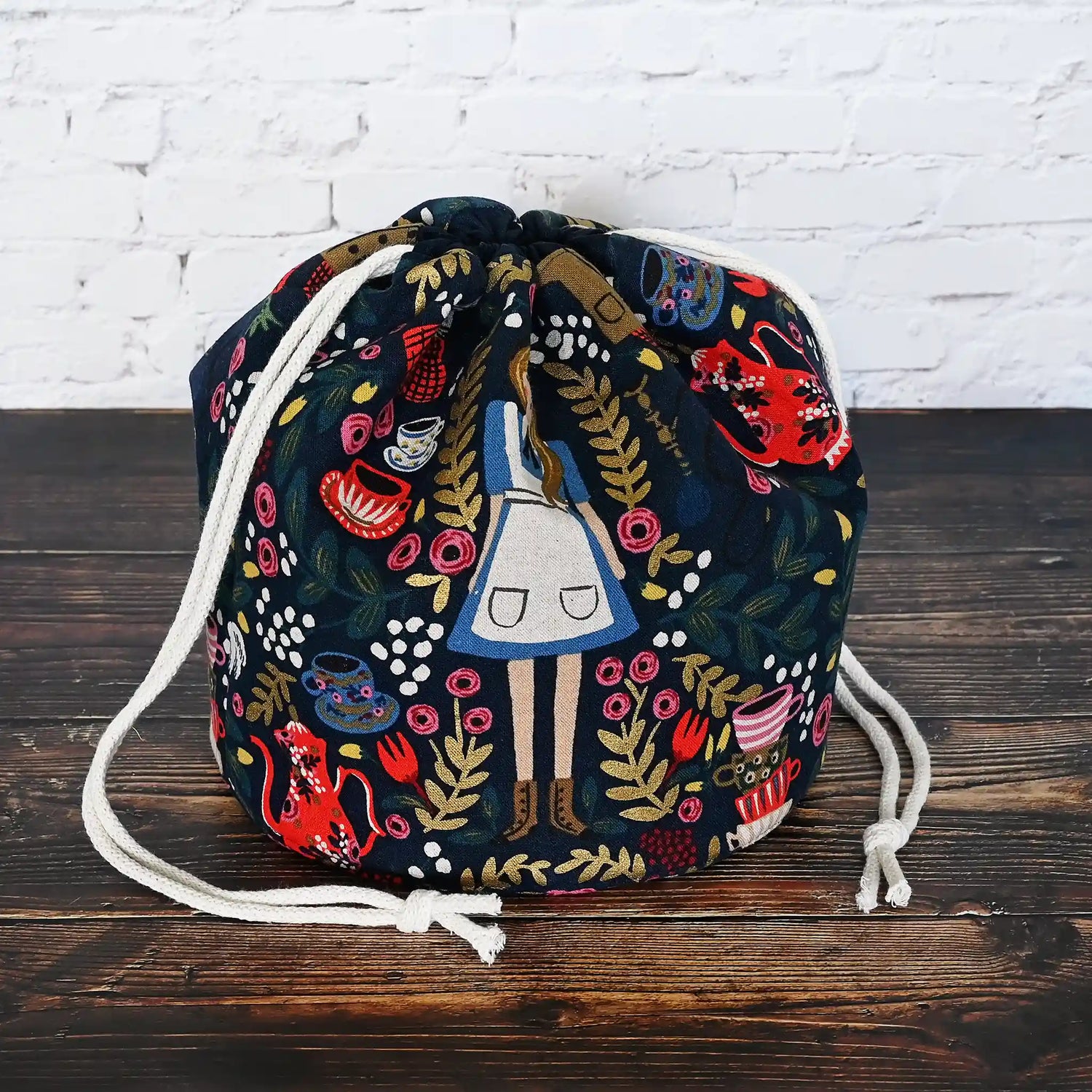Gorgeous navy bucket bag made from canvas with a beautiful Alice in Wonderland pattern.  It has lots of pockets and is structured to stand alone.  Made in Canada by Yellow Petal Handmade.