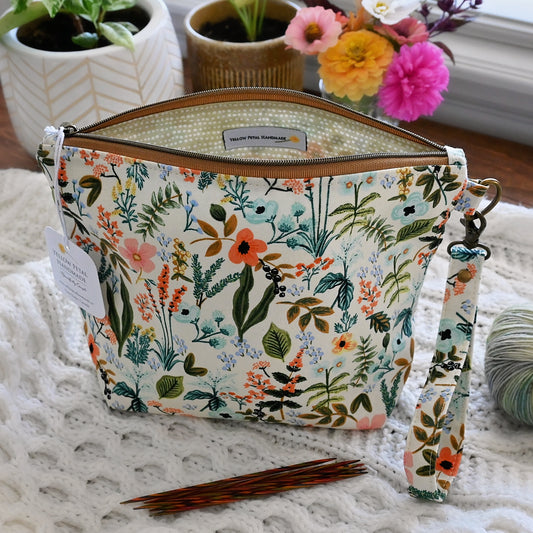 Floral-patterned project bag with a strap and zipper closure in Rifle Paper Co's Amalfi cotton, surrounded by plants and yarn.  Made in Canada by Yellow Petal Handmade.