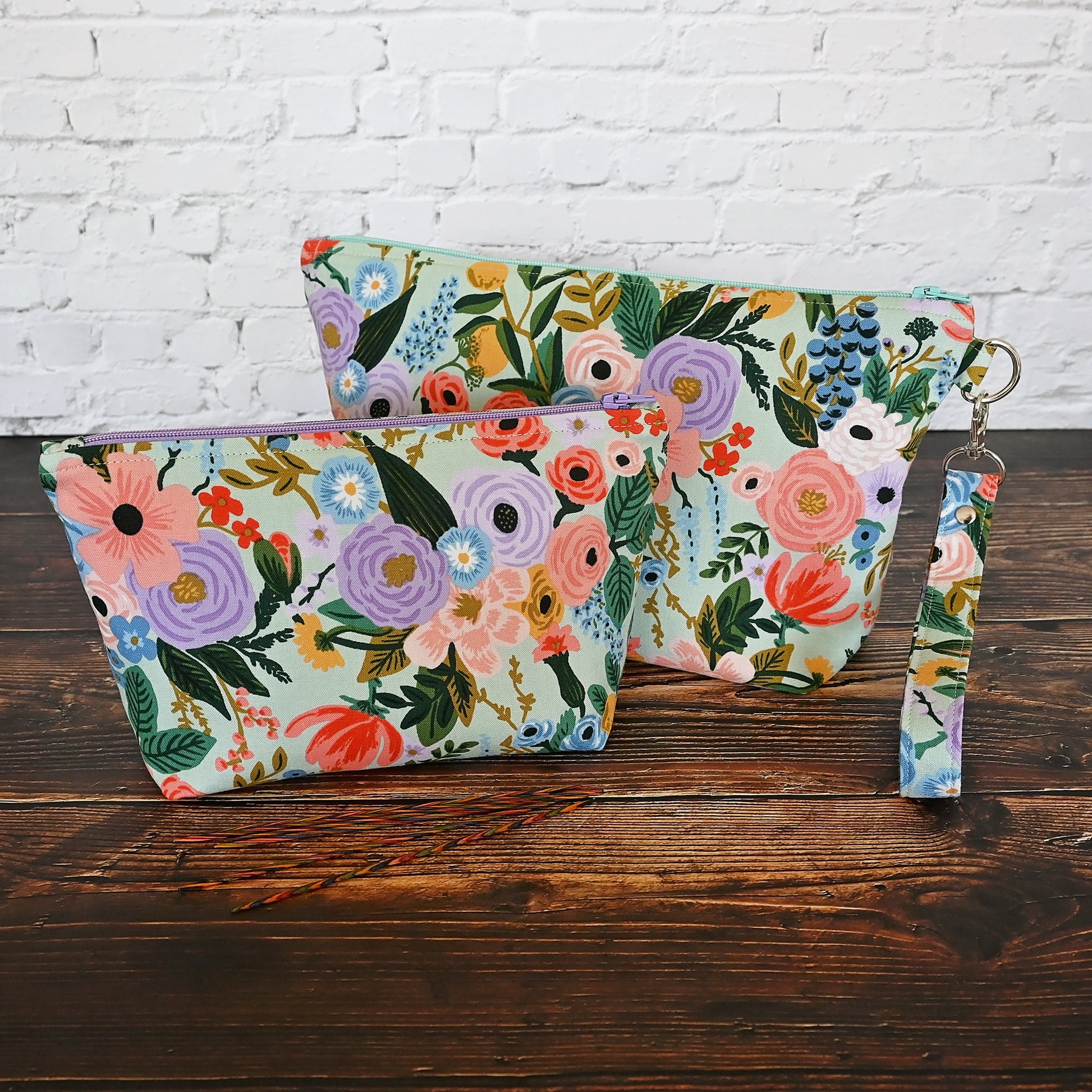 Aqua floral pouch with zipper closure and a removable wrist strap.  Made from Rifle Paper Co's newest garden party collection and lined in a pale pink spotty fabric.  Made in Canada by Yellow Petal Handmade.