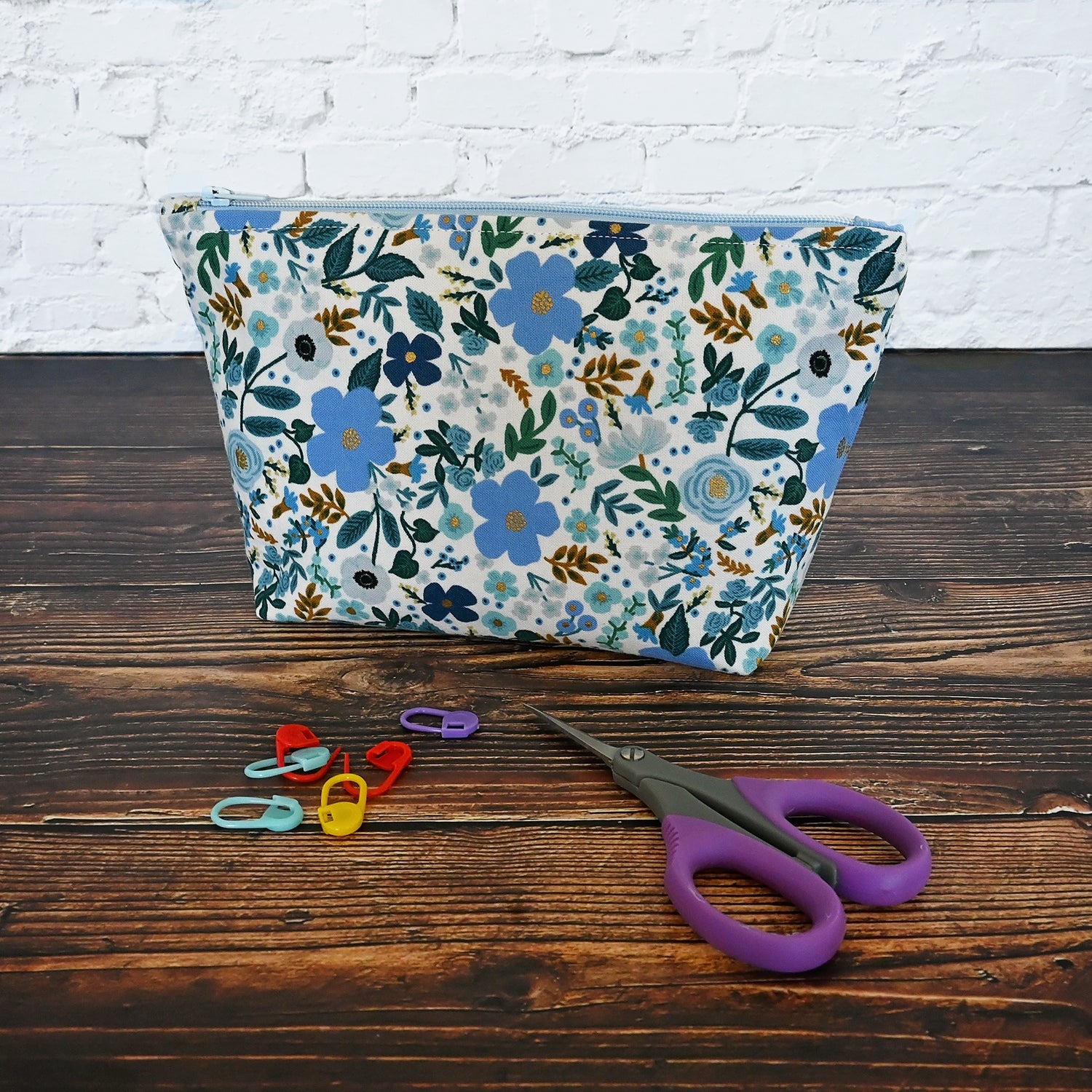 Pretty blue floral accessory pouch in fabric from Rifle Paper Co.  This pouch features a blue floral with small gold metallic details, and is lined in a blue and white fabric.  It closes securely with a pretty blue zipper.  Great for all of your acessories!