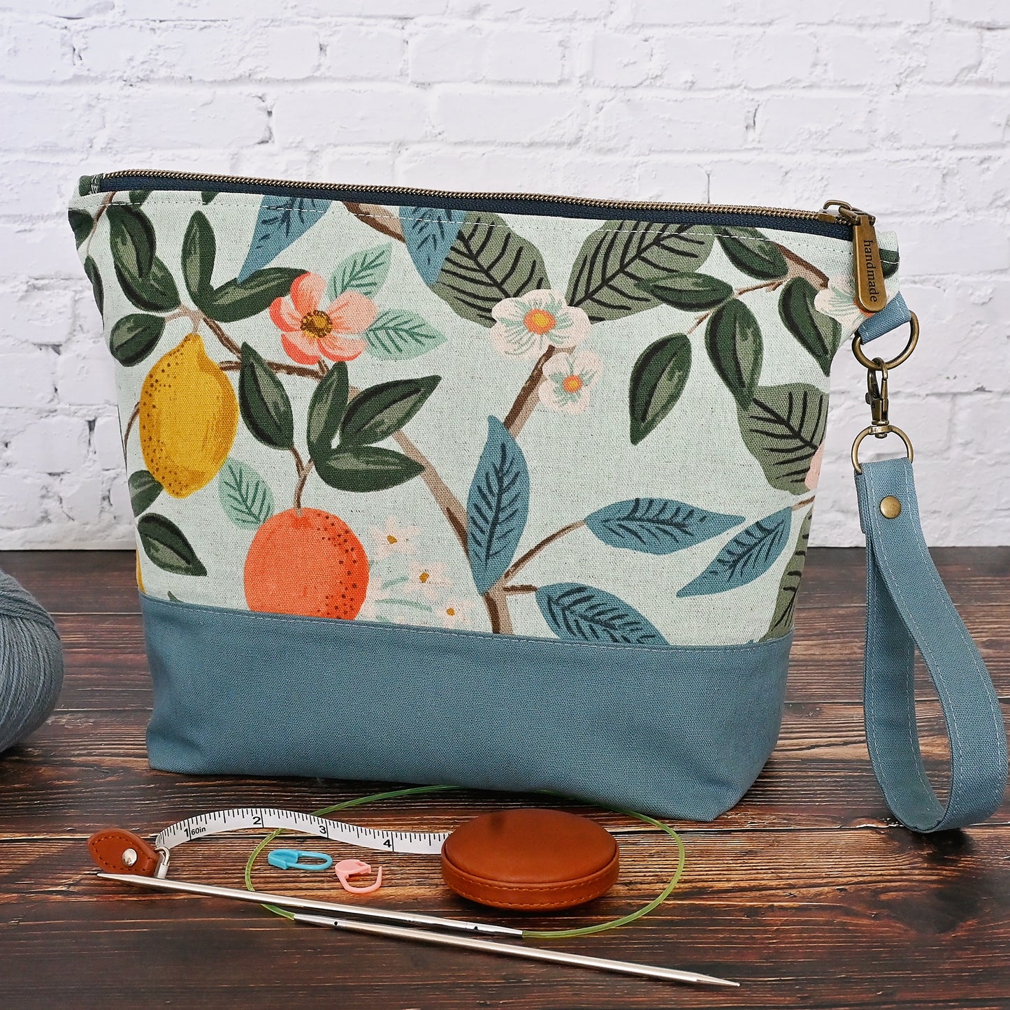 Lovely canvas project bag in Rifle Paper Co's Bramble collection.  Made from an aqua canvas featuring citrus fruit and flowers.  The exterior is paired with a lovely blue grey linen by Robert Kaufman, and the interior, including pockets, is made from a pretty aqua and white cotton.  This bag features a lovely high quality zipper and a removable wrist strap.  Made in Canada by Yellow Petal Handmade.