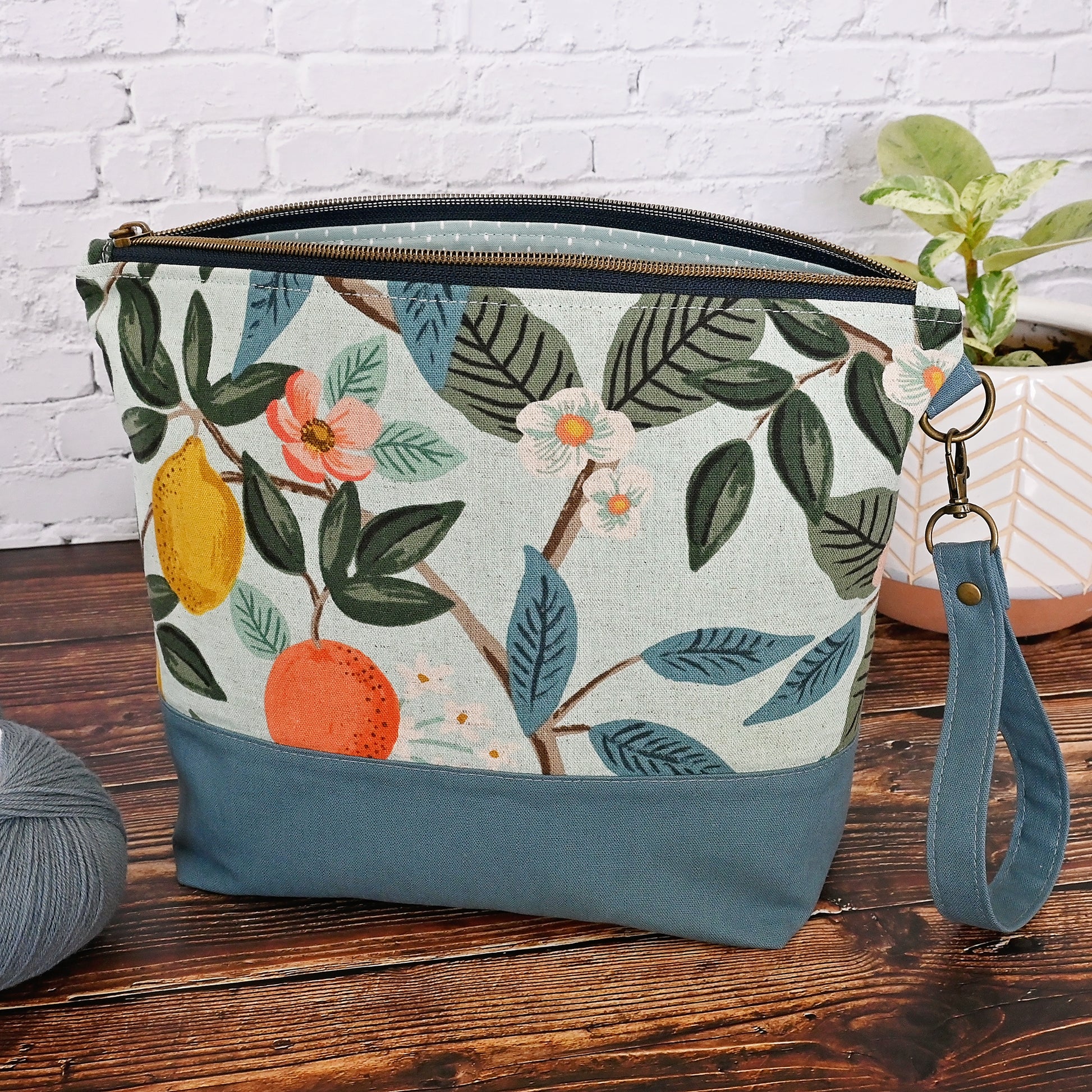 Lovely canvas project bag in Rifle Paper Co's Bramble collection.  Made from an aqua canvas featuring citrus fruit and flowers.  The exterior is paired with a lovely blue grey linen by Robert Kaufman, and the interior, including pockets, is made from a pretty aqua and white cotton.  This bag features a lovely high quality zipper and a removable wrist strap.  Made in Canada by Yellow Petal Handmade.