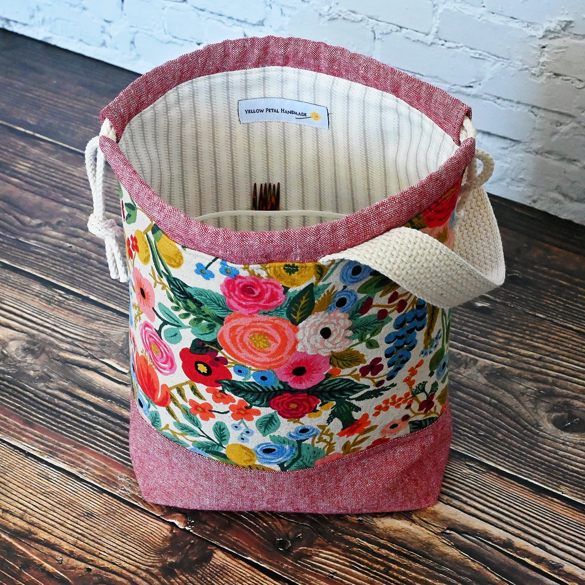 Small project bag with pockets, and handle and a drawstring closure.  This bag is made from Rifle Paper Co's Garden Party canvas and is paired with a red yarn dyed linen by Robert Kaufman.  Inside features pockets and a cotton lining in a cream and grey stripe.  Made in Canada by Yellow Petal Handmade.