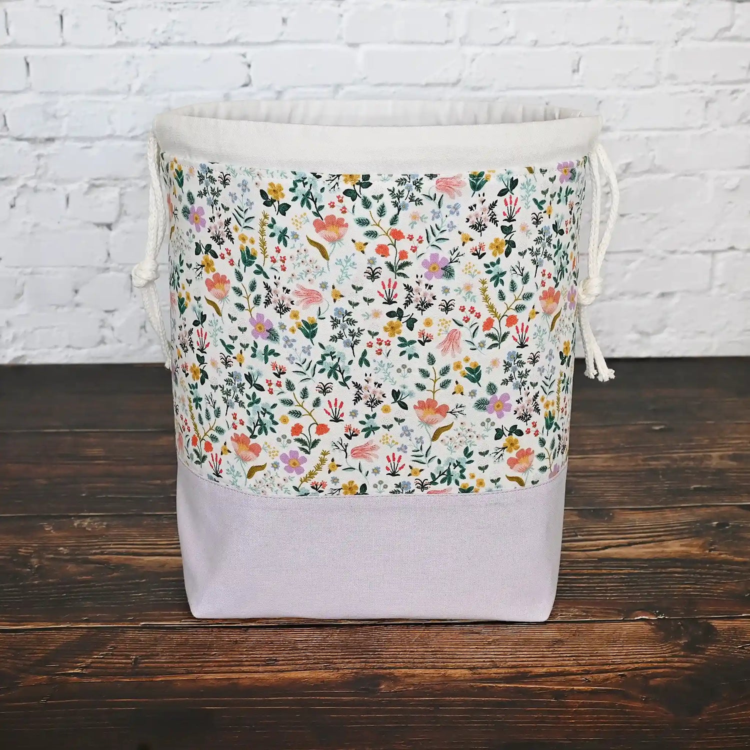 Pretty white floral and mauve linen drawstring project bag in Rifle Paper Co's Curio fabric.  The interior is a pretty mauve fabric with pockets.  Made in Nova Scotia, Canada by Yellow Petal Handmade.