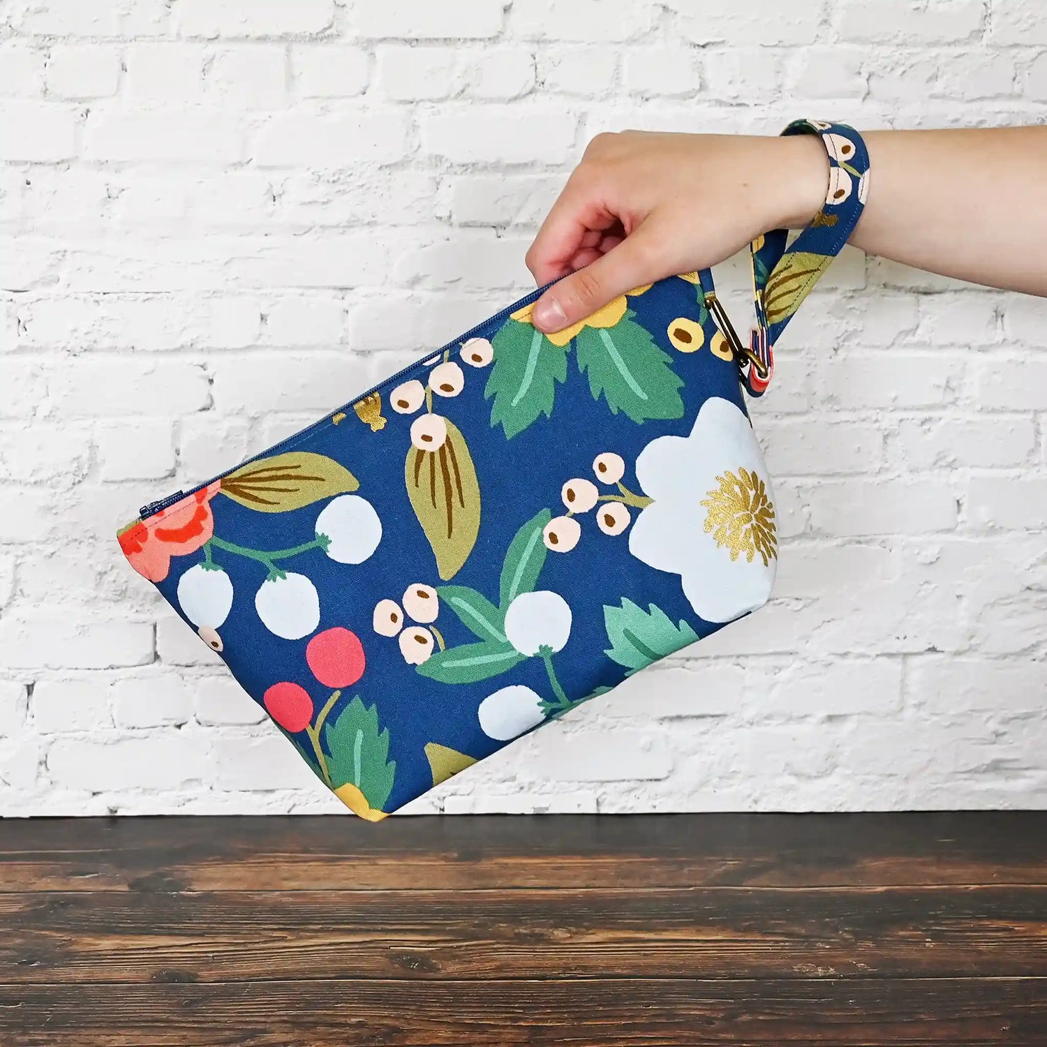 Blue floral canvas zippered pouch with removable wrist strap, lined in a pretty pink cotton.  Made with fabric from Rifle Paper Co and Riley Blake.  Handmade in Canada by Yellow Petal Handmade.