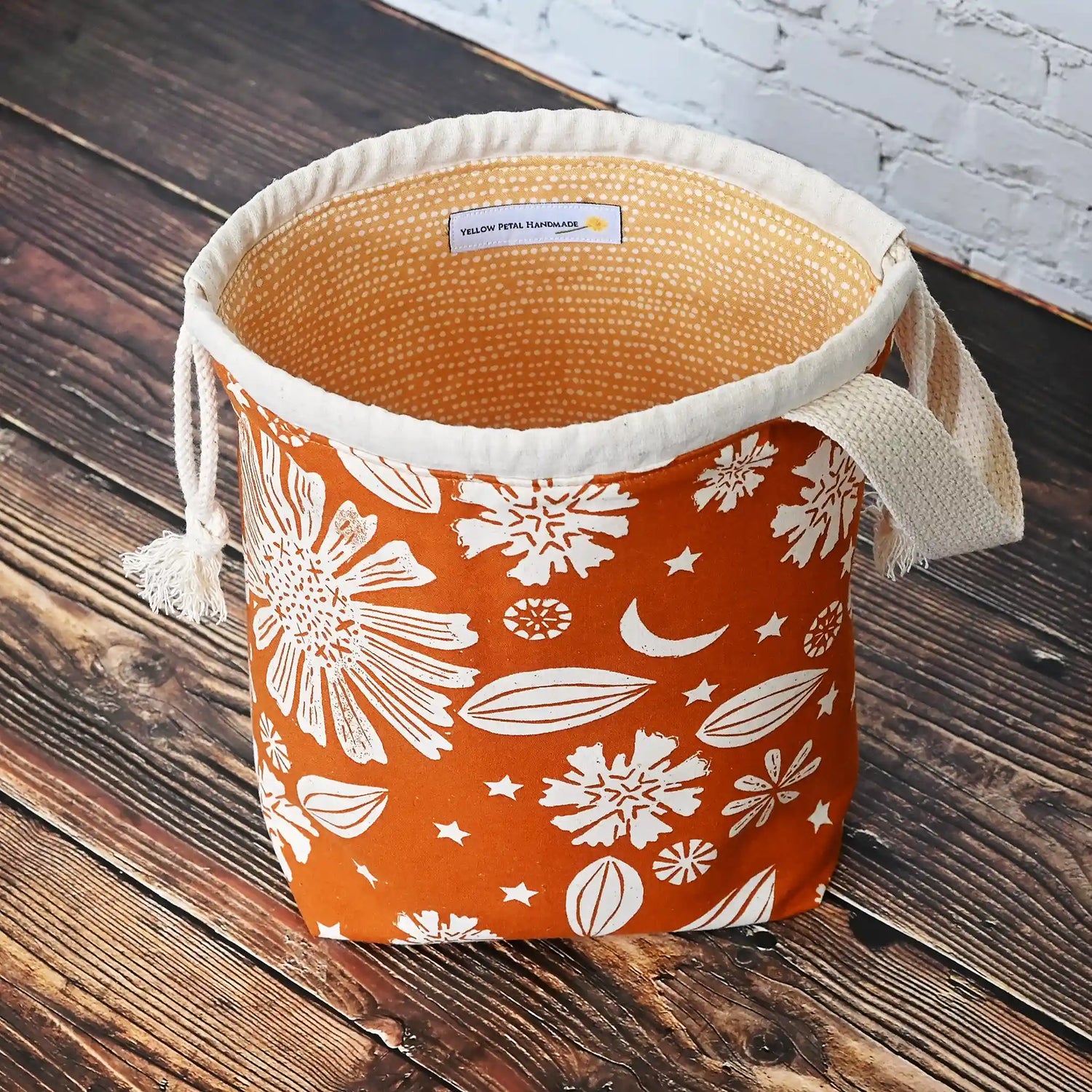 Beautiful drawstring project bag with handle in a burnt orange floral and star fabric and lined in a fun gold dotty cotton.  Handmade in Nova Scotia Canada by Yellow Petal Handmade.