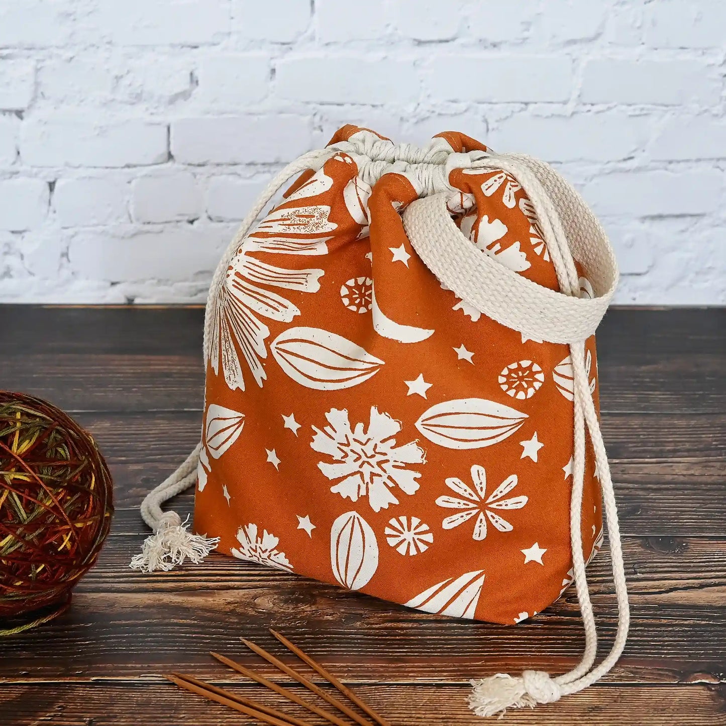 Beautiful drawstring project bag with handle in a burnt orange floral and star fabric and lined in a fun gold dotty cotton.  Handmade in Nova Scotia Canada by Yellow Petal Handmade.