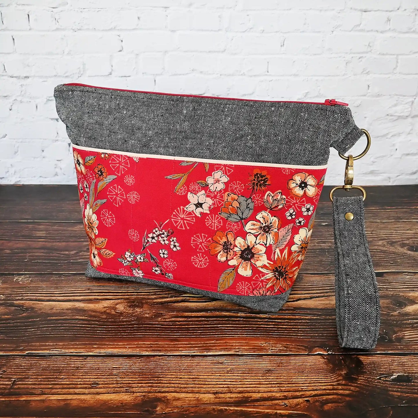 Beautiful grey linen project bag with red floral exterior pockets in  premium Art Gallery cotton.  Comes with a removal wrist strap. Made in Nova Scotia Canada by Yellow Petal Handmade.
