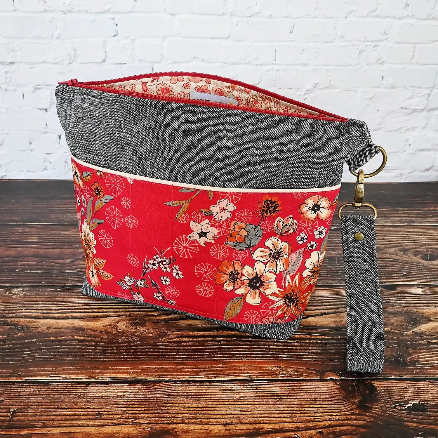 Beautiful grey linen project bag with red floral exterior pockets in  premium Art Gallery cotton.  Comes with a removal wrist strap. Made in Nova Scotia Canada by Yellow Petal Handmade.